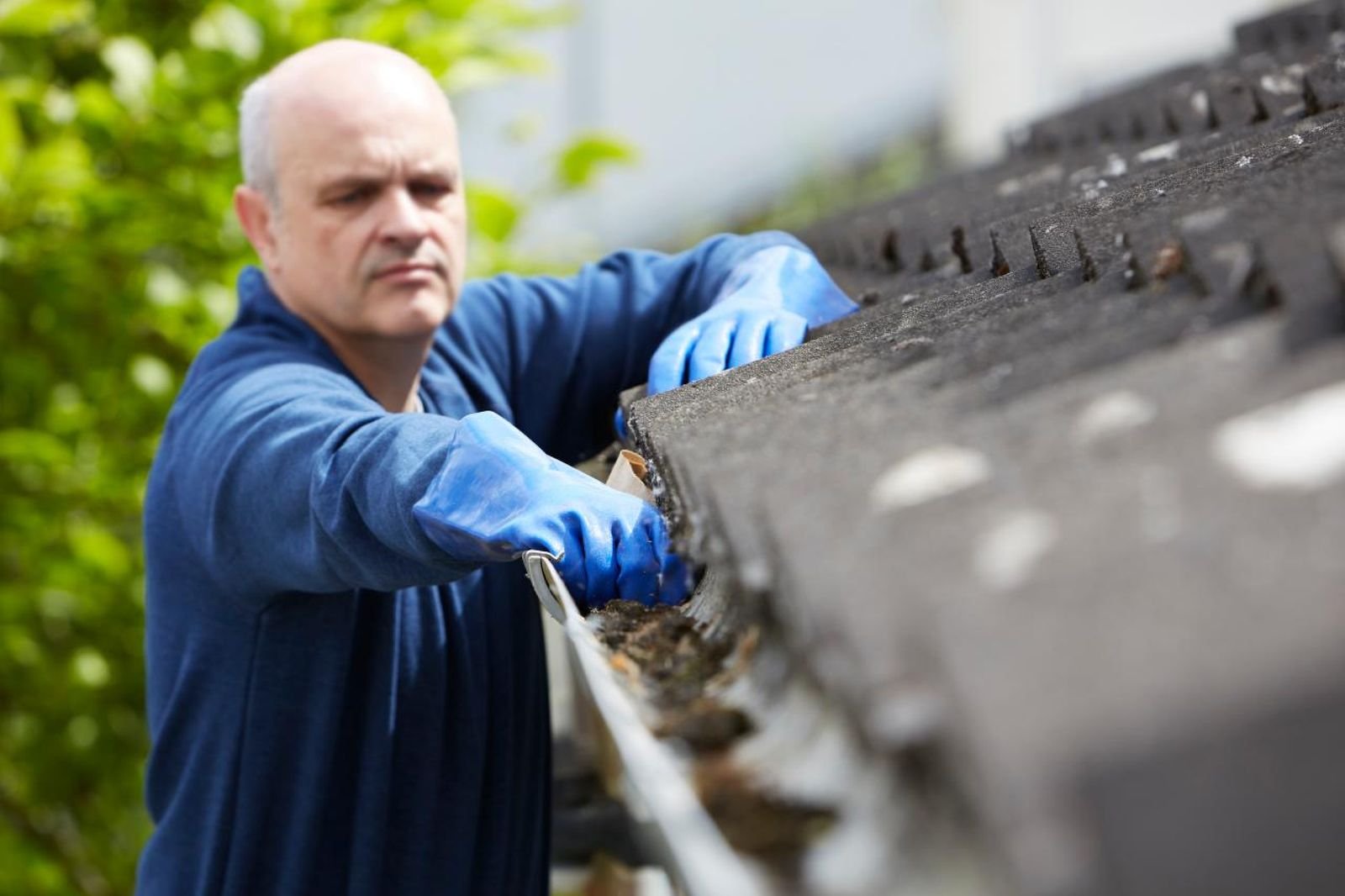 Technician professionally cleaning debris out of a gutter